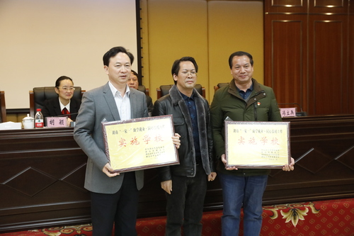 湖南中华职教社副秘书长冯立兵（中）向湖南铁路科技职院和湖南汽车工程职院授予“湖南‘一家一’·同心温暖工程实施学校”牌匾